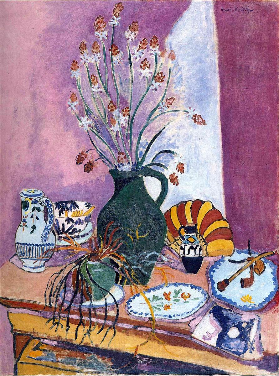 A Fauvist still life with a tall green jug of asphodels at center, patterned plates and ceramics on a diagonally tilted table, a fan-like shell and small violin at right, and mauve-lavender walls with a vertical white stripe; bold outlines and flat, saturated colors create a decorative, modern interior.
