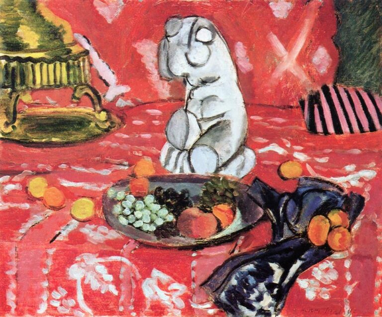 On a red patterned tablecloth, a small white plaster torso stands beside a shallow dish of grapes, peaches, and berries; at left a gilt stand intrudes, and at right a folded indigo fabric spills apricots, creating a richly colored, decorative still life.