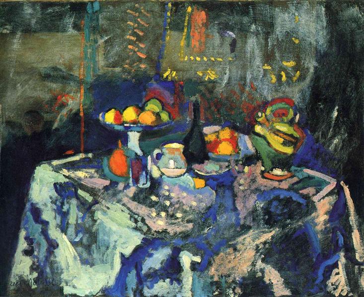 Fauvist still life of a blue-violet tablecloth set with a compote of fruit, white jug, dark bottle, plate with oranges, and a green lidded jar; objects glow against a dark, patterned background with yellow dashes and soft shadows.