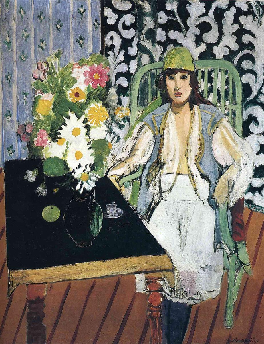 Woman in green chair wearing a green cap and pale blue vest sits beside a triangular black table holding a bouquet, a green apple, a small cup, and a dark jug; background split between lavender striped curtain and dark wall with white arabesques; reddish diagonal floorboards; painted with bold black, mint green, lavender, warm ochre, and vivid floral accents.