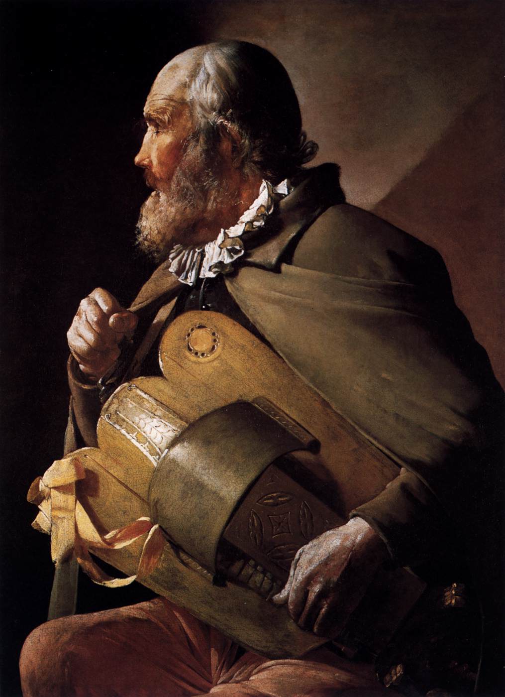 Half-length profile of an elderly blind hurdy-gurdy player wearing a cloak and ruffled collar, cradling a large instrument across his chest with one hand on the crank and the other steadying the body, warm light modeling scalp, beard, wood, and hands against a dark background.