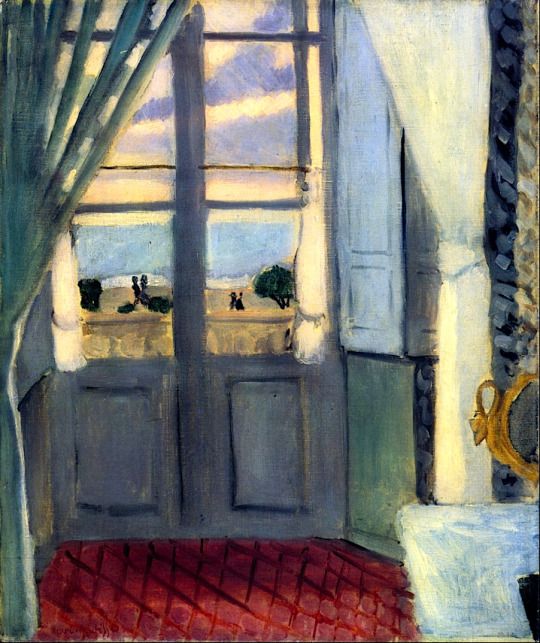 Interior with closed French doors centered; red lattice-tiled floor in foreground, pale curtains and shutter at sides, small gilt mirror on right, and through the panes a calm band of promenade, sea, and lavender-streaked sky.