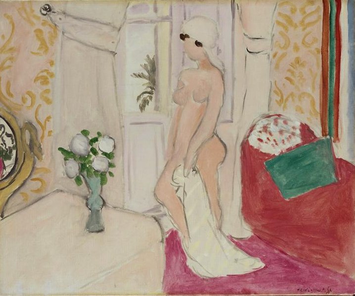 A softly colored interior with patterned yellow wallpaper, a pink carpet, and a red divan; at center a nude woman in profile stands before a pale door or window holding a white drape, while a small vase of white flowers sits on a table at left, all painted with simplified contours and calm pinks, creams, and greens.