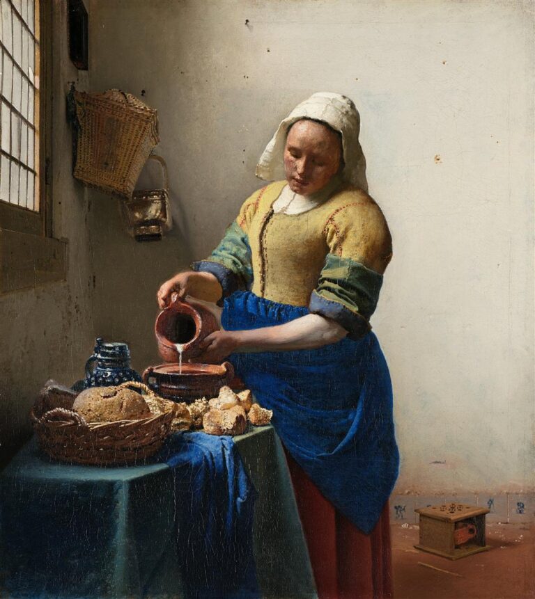 In a sunlit Delft kitchen, a maid in a yellow bodice and blue apron steadily pours milk from a red earthenware pitcher into a bowl beside bread, a wicker basket, and a stoneware jug, with a small foot warmer on the floor and a leaded-glass window at left.