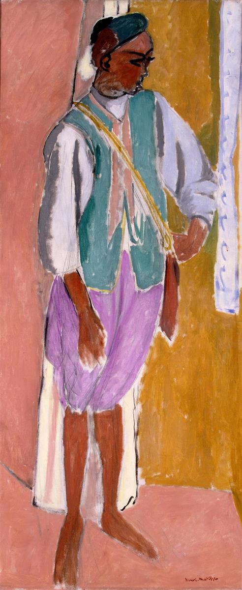Tall vertical portrait of a barefoot Moroccan man standing against simple ochre and pink planes with a cool blue-white strip at right; he wears a green cap, mint vest over a pale shirt, lilac trousers, and a diagonal gold sash; one hand rests on his hip, the other hangs at his side; features and edges defined by confident dark painted contours in Henri Matisse’s 1912 “The Moroccan Amido.”