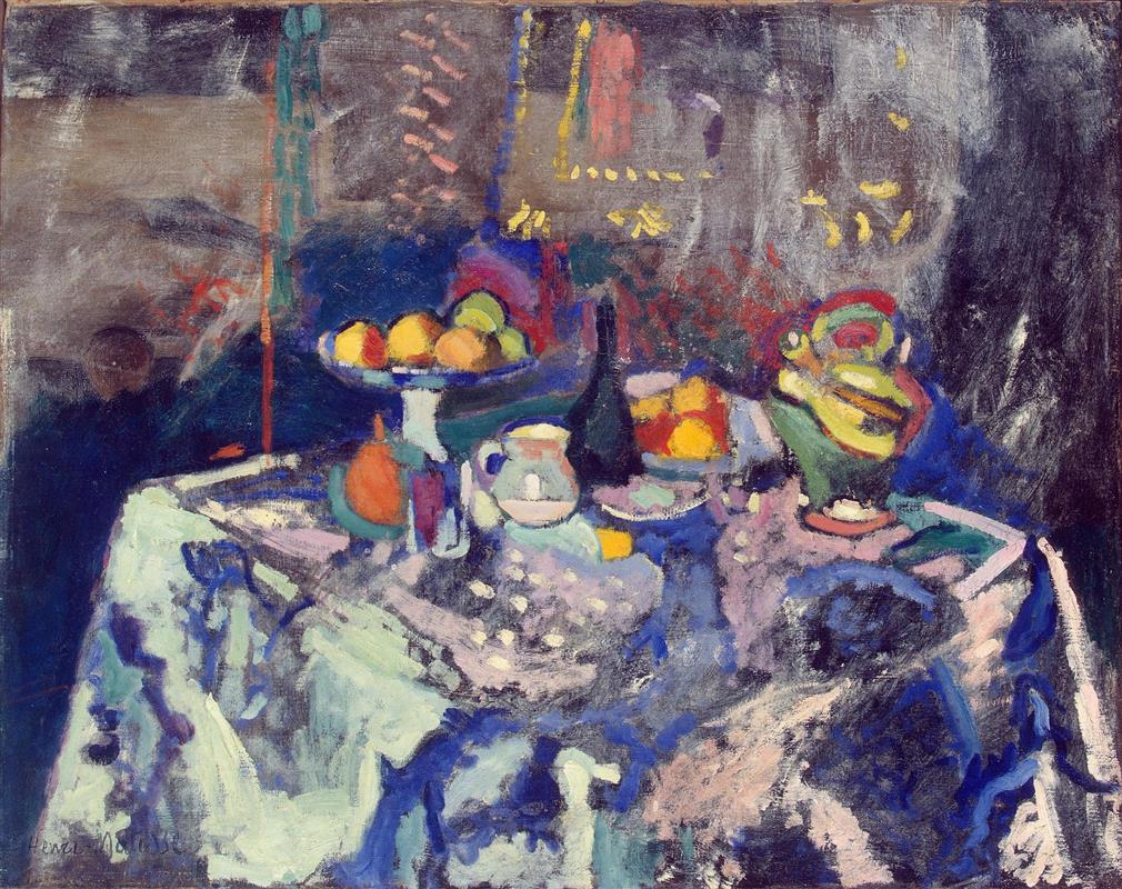 Henri Matisse’s “Vase, Bottle and Fruit” (1906) shows a tabletop with a white pedestal compote piled with oranges and lemons, a dark green bottle, a small jug, and a green-yellow handled vase on a pale blue-violet cloth; a dark, atmospheric background with small yellow and pink accents surrounds the luminous arrangement.