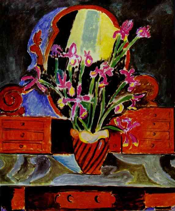 A 1912 still life by Henri Matisse showing a striped red vase of magenta and lilac irises on a marbled tabletop before an oval mirror that glows with yellow and blue light, flanked by red drawers and scrolls, all set against a dark ground that intensifies the vivid colors.