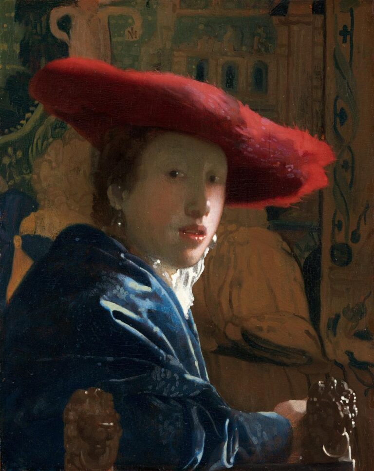 Close-up of a young person turning toward the viewer, wearing a bright red, wide-brimmed hat and a deep blue mantle; soft daylight illuminates the face, a pearl earring glints, and carved chair finials and a muted tapestry frame the intimate scene.