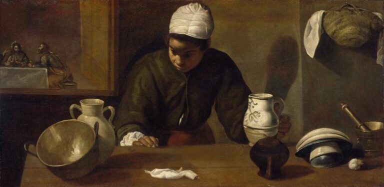 Wide kitchen interior with a young maid in a white headscarf wiping a wooden counter, surrounded by a tilted brass bowl, earthen jars, a white-glazed jug, stacked plates, and a mortar; through a small opening at left, Christ appears at table at the Supper in Emmaus.
