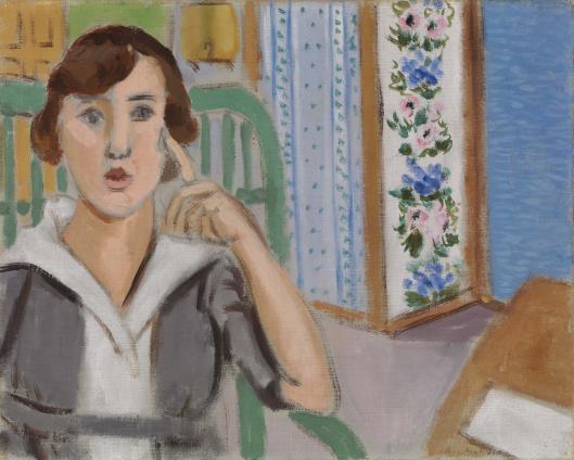 A woman in a gray dress with a white collar sits in a green chair, finger to her temple, beside a folding screen with blue dots and pink-blue floral bands; a small table with a sheet of paper and a blue wall complete the light, airy interior.