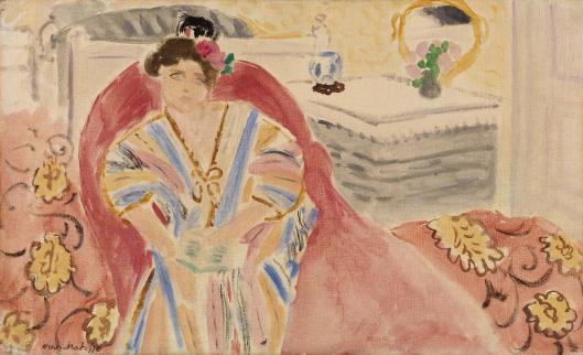 A woman in a pastel-striped robe sits on a deep red sofa in a bright room; behind her a table with small objects and a round mirror reflects light, while patterned upholstery and soft colors create a serene interior.