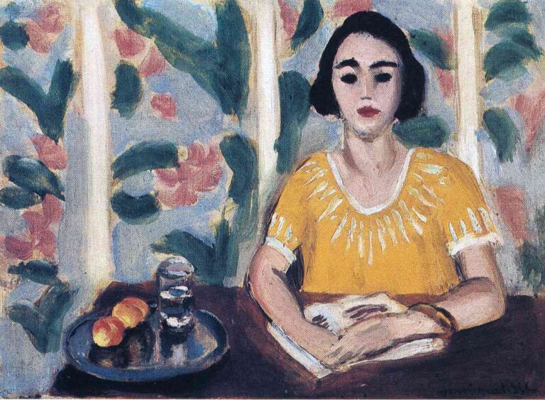 A woman in a vivid yellow blouse sits at a dark table reading an open book; to her left a metal tray holds two water glasses and two peaches, while a pale wall behind is painted with broad green leaves and pink blossoms.