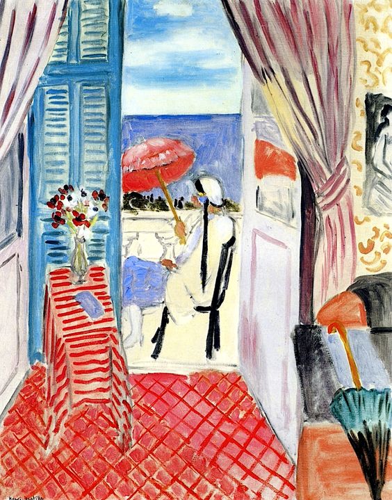 View from a room onto a seaside balcony: red-tiled floor and striped table with flowers in the foreground, blue shutters at left, mauve curtains at right, and a seated woman in white holding a red umbrella against sky and water beyond, painted with loose, luminous brushstrokes.