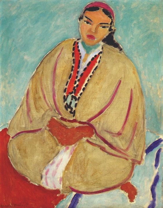 Seated Moroccan woman in a large yellow burnous outlined with rose, hands folded at her lap, a red-and-black central braid or necklace, and a pink headband; set against a flat turquoise background with small red and blue touches at the lower edge; simplified face and forms defined by confident painted contours in Henri Matisse’s 1912 “Zorah in Yellow.”