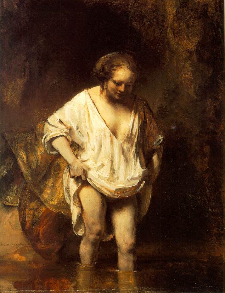 Rembrandt painting of a woman wading in shallow water, head bowed as she lifts the hem of a white linen shift; warm drapery rests on the bank and soft light models her skin against a dark, atmospheric background.