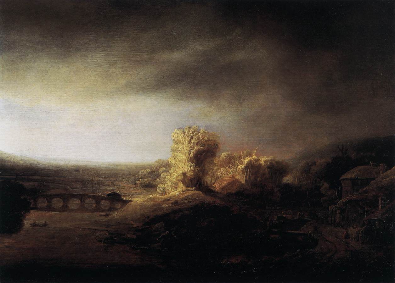 Wide landscape by Rembrandt showing a long multi-arched bridge over a river, a sunlit grove on a hill, and a vast darkening sky; distant plain fades to pale haze while a curving road and cottages sink into shadow at right.