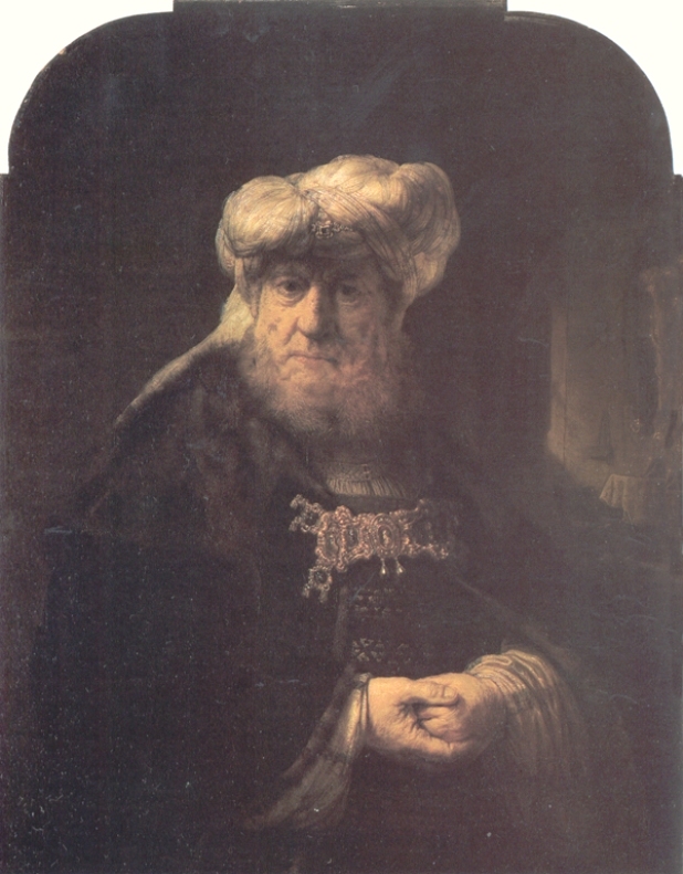 Half-length portrait by Rembrandt of an elderly man in a tall white turban and dark jeweled robe, softly lit against a deep background; his hands rest together while a faint room glows at the right, emphasizing calm authority and rich textures.