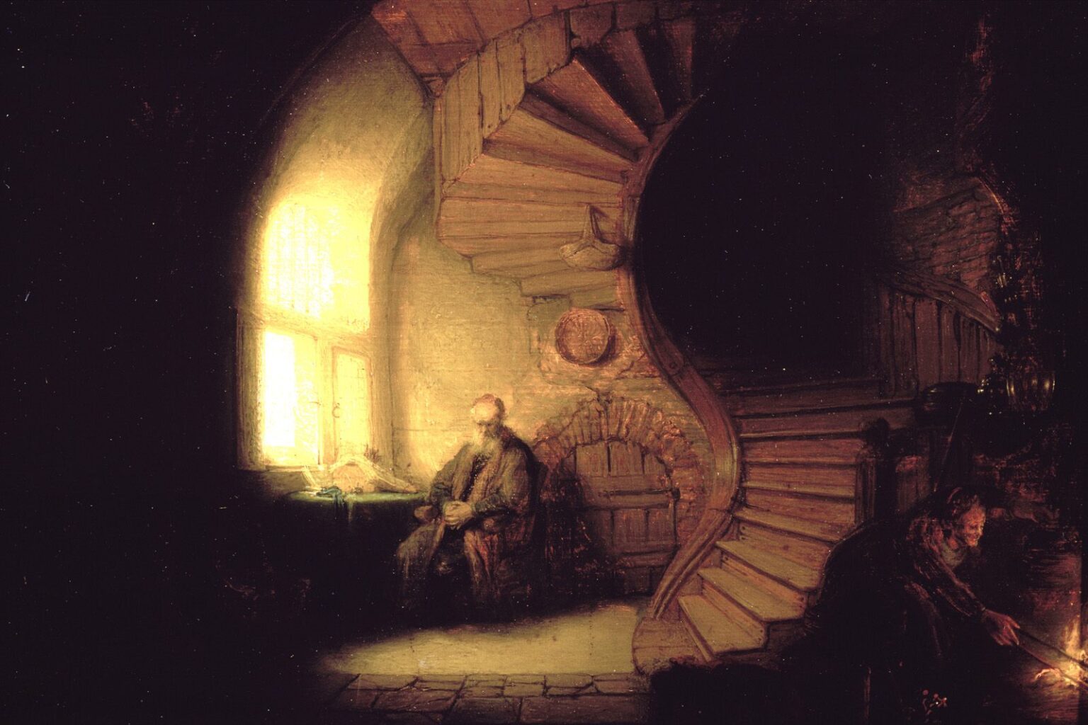 Dim interior by Rembrandt with sunlight pouring through a window onto a seated philosopher beside a table; a large spiral staircase curves into darkness at right while a servant tends a small fire below, creating a dialogue between daylight and hearth glow.