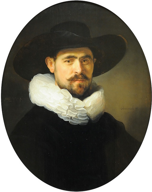 Oval portrait of a bearded man wearing a broad black hat and brilliant white ruff against a dark background, his warm face softly lit with a composed, attentive gaze.