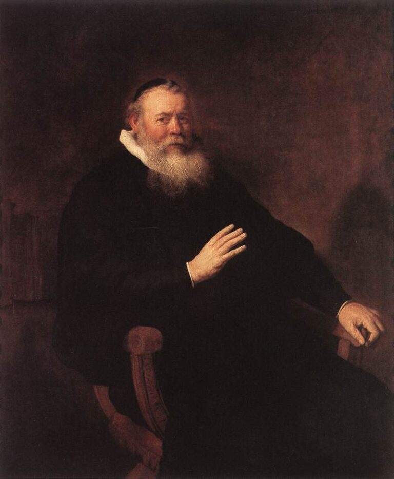 Seated bearded minister in a dark robe and small white ruff, one hand lifted gently as if in greeting or blessing, the other resting on a wooden chair; warm brown background and soft side lighting focus attention on the expressive face and gesture.