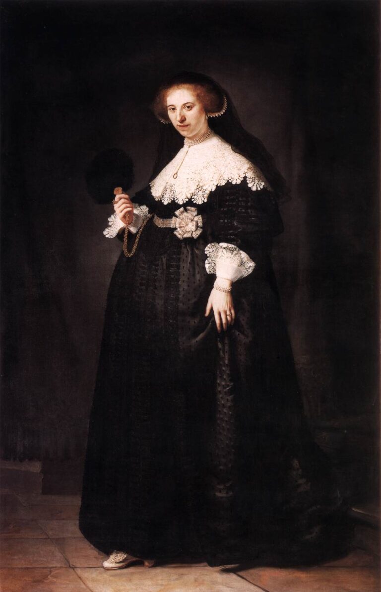Full-length portrait of Oopjen Coppit standing on a tiled floor in a rich black gown with brilliant lace collar and cuffs, pearls, veil, and fan in hand, softly illuminated against a dark interior, painted by Rembrandt in 1634.
