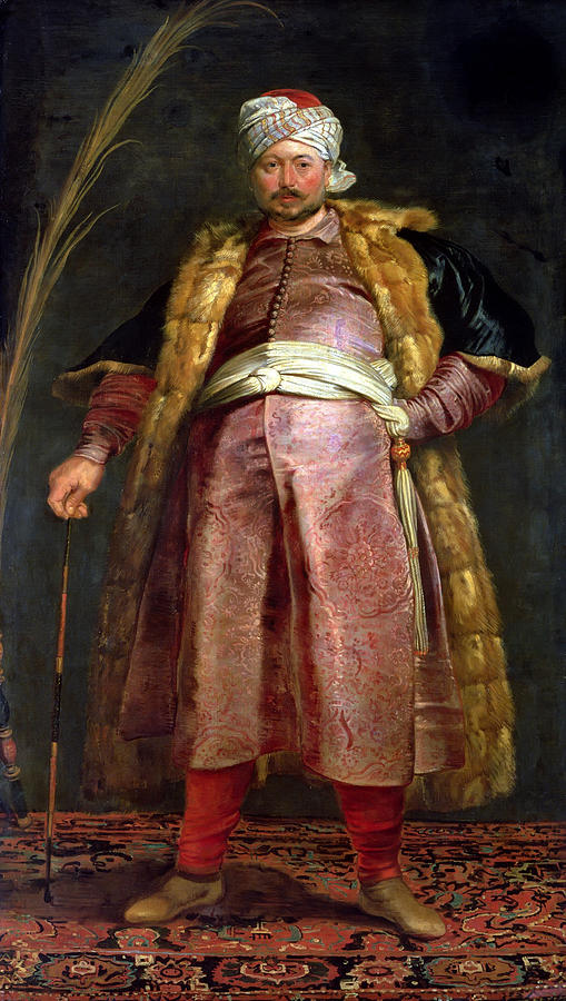 Full-length portrait of Nicolas De Respaigne standing on an ornate carpet, wearing a fur-lined coat, embroidered red robe, white sash, and turban, holding a cane against a dark background.